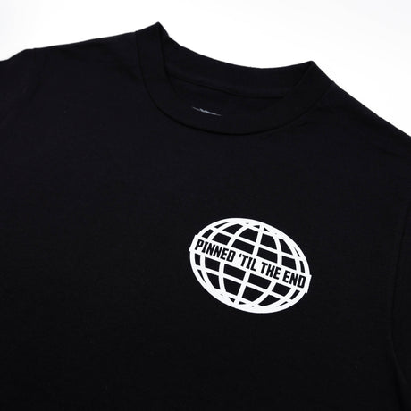 Black T-shirt close-up of white globe logo reading “Pinned Til The End”