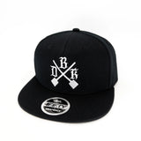 Black snapback back with white cross logo and circular side brand patch