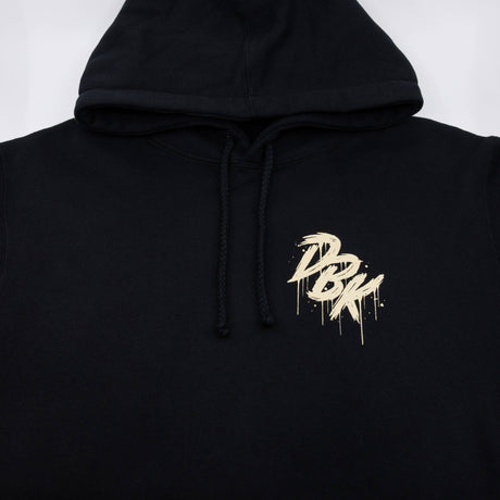 Black hoodie hood drawstrings with small gold logo graphic on front