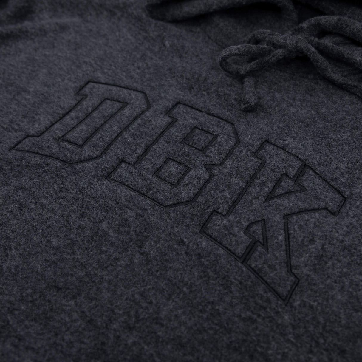 Women’s dark charcoal pullover hoodie close-up of logo graphic and hood drawstrings