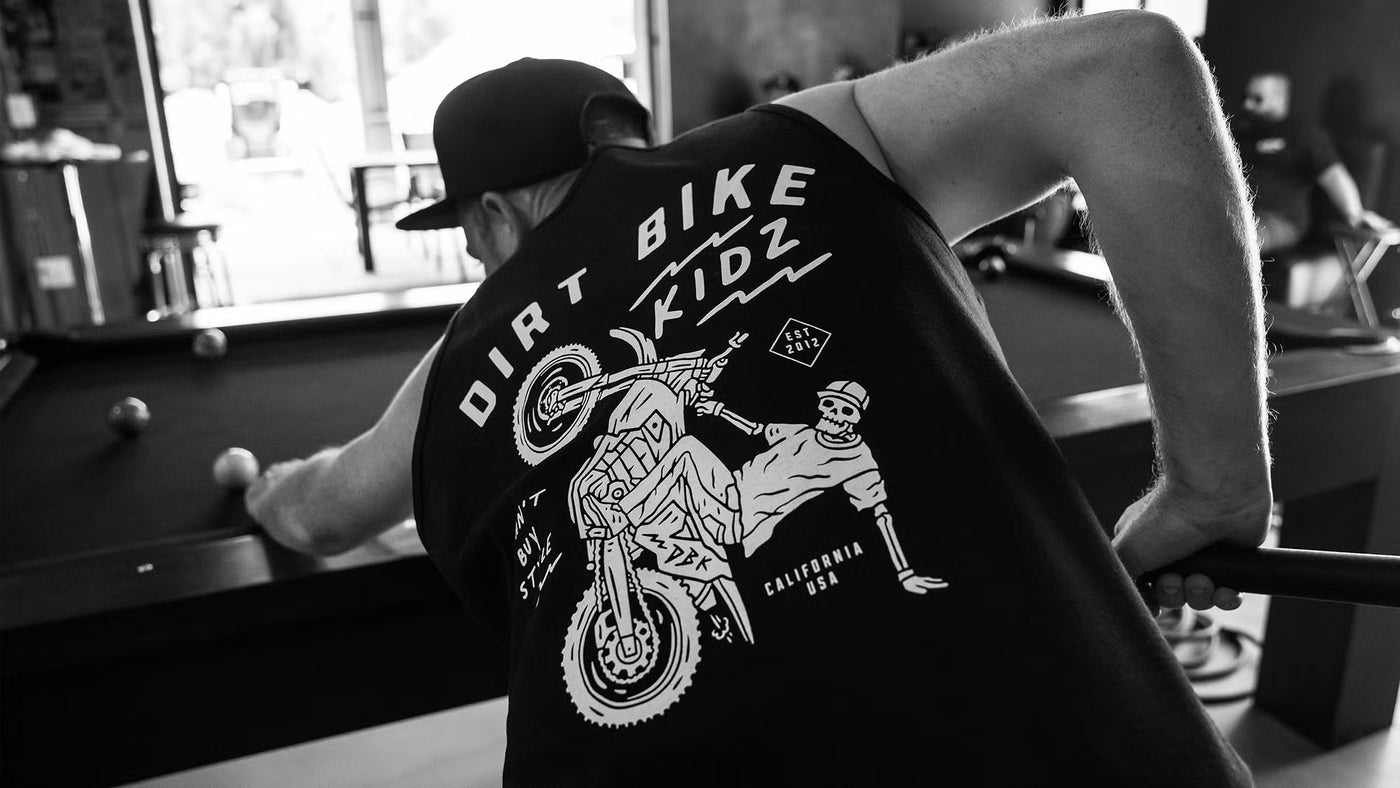 Person wearing a black tank top with 'Dirt Bike Kidz' graphic design, in a casual setting.