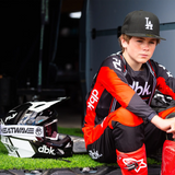Youth motocross jersey in black with red-orange sleeves and white trim, long sleeves