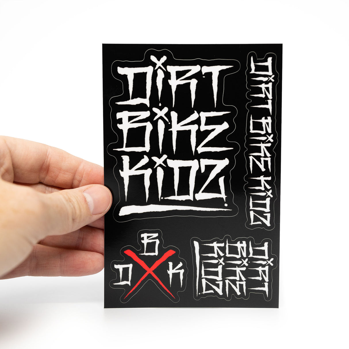 Hand holding sticker pack sheet with white graffiti lettering on black and red X