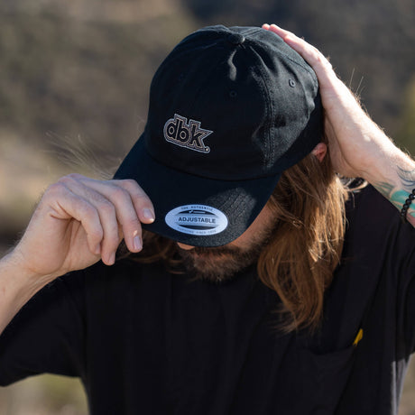 Black dad hat on model with dbk front logo and Adjustable label