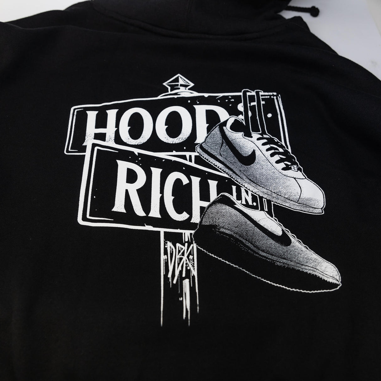 Close-up of black hoodie back print: HOOD RICH with sneaker graphic