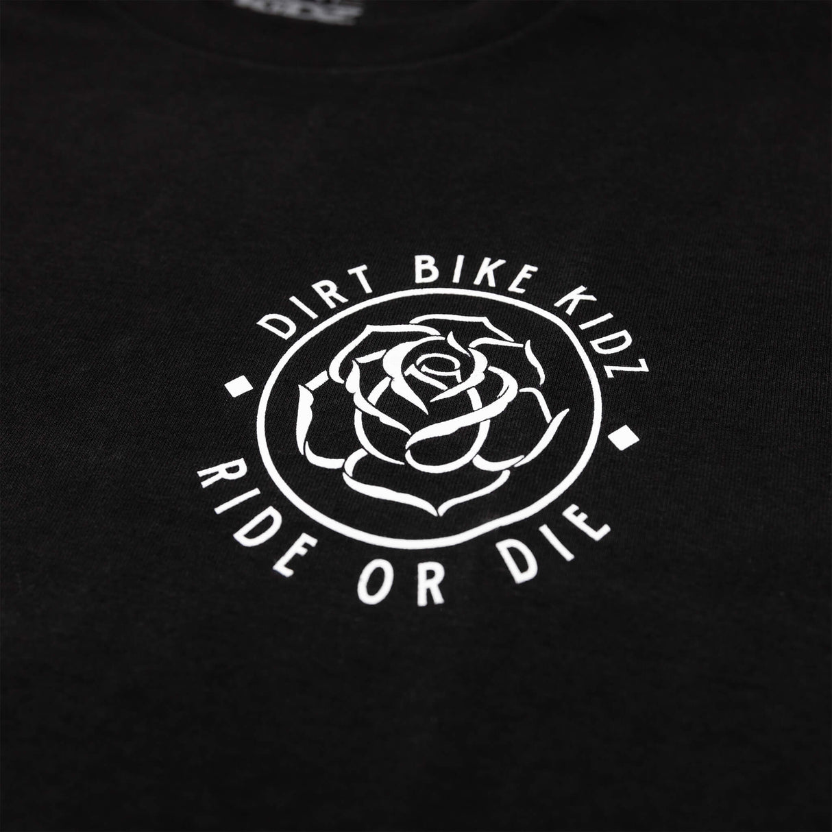 Close-up of black t-shirt chest logo: outlined rose in a circular badge