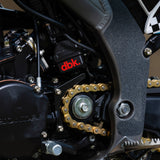 Motorcycle engine area with dbk logo and gold chain on black frame