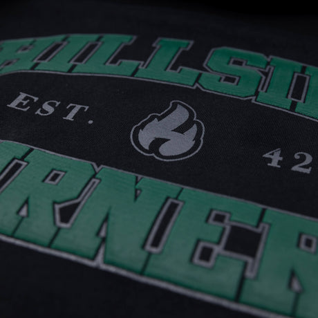 Close-up of flame icon and Est. text on black varsity hoodie with green lettering
