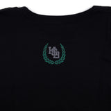 Black varsity tee with small green crest logo on chest