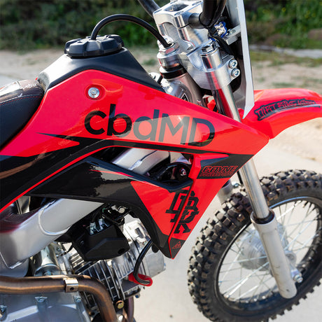 Honda CRF 110 fuel tank close-up in red with cbdMD decal and front fork
