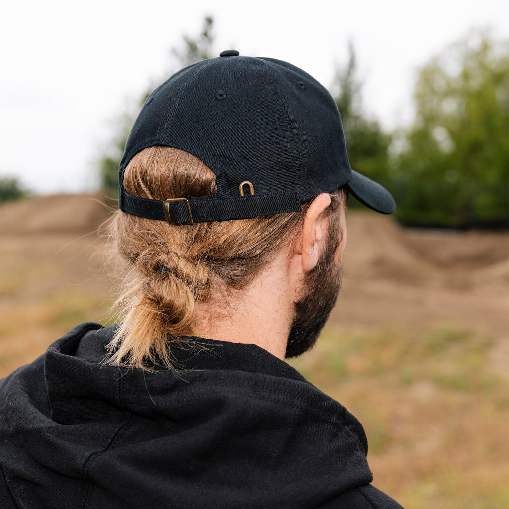 Black dad hat from back with adjustable strap and metal buckle detail