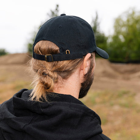 Black dad hat from back with adjustable strap and metal buckle detail