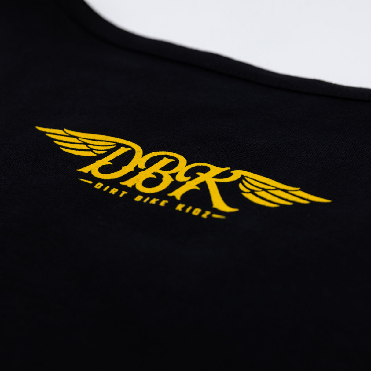 Black tank top close-up of yellow DBK wing logo across chest