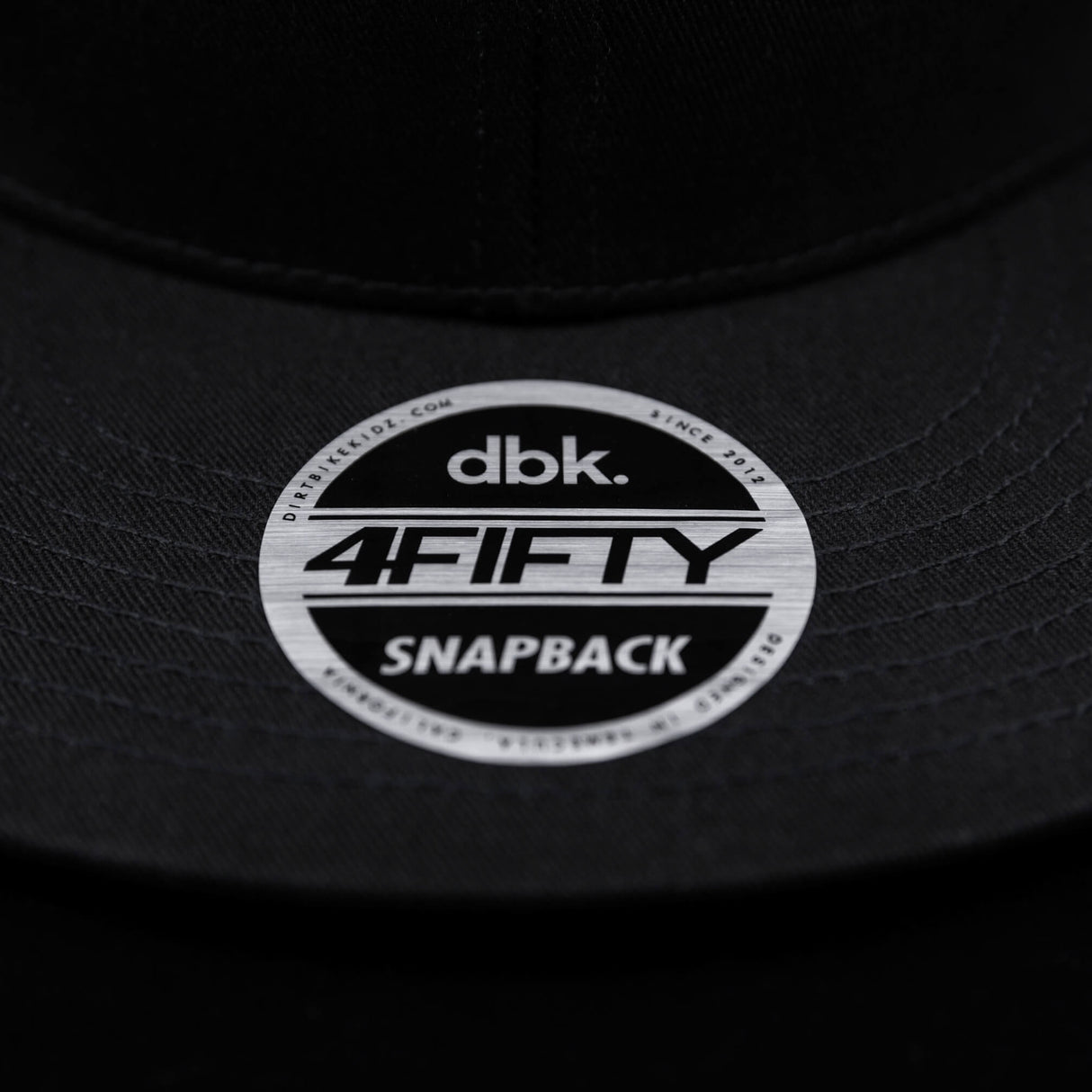 Snapback brim sticker showing “dbk 4FITY SNAPBACK” on black cap