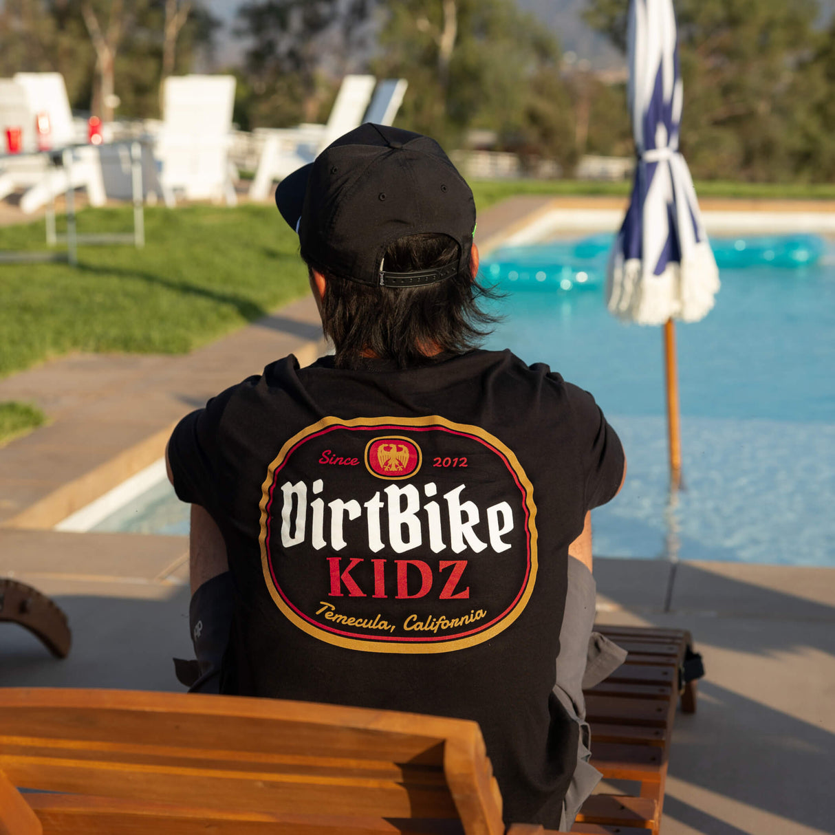 Premium tall tee, black, with DirtBike KIDZ oval back logo graphic worn by person