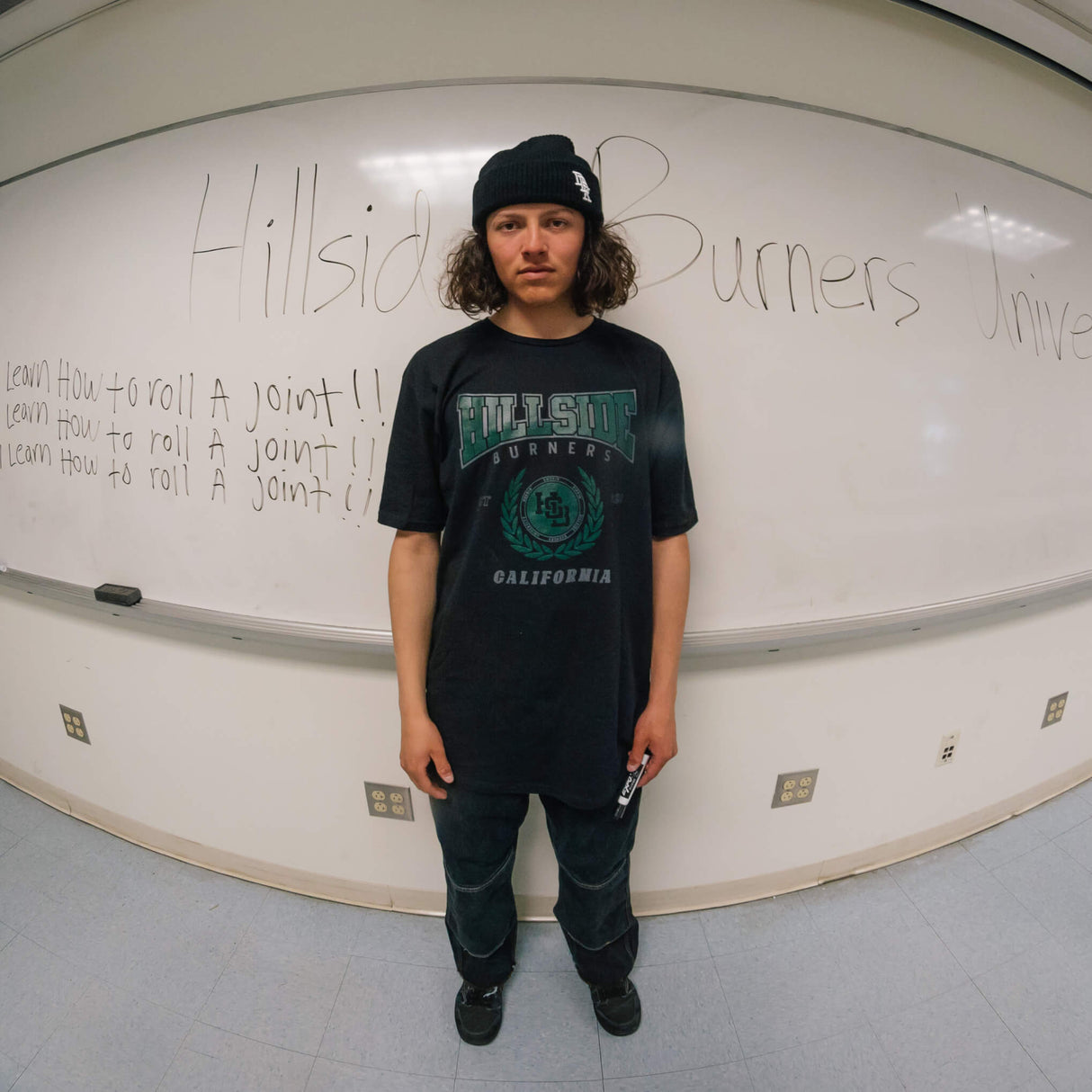 Black varsity tee worn by model with green front “Burners California” print