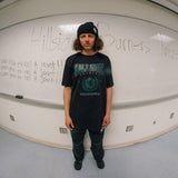 Black varsity tee worn by model with green front “Burners California” print