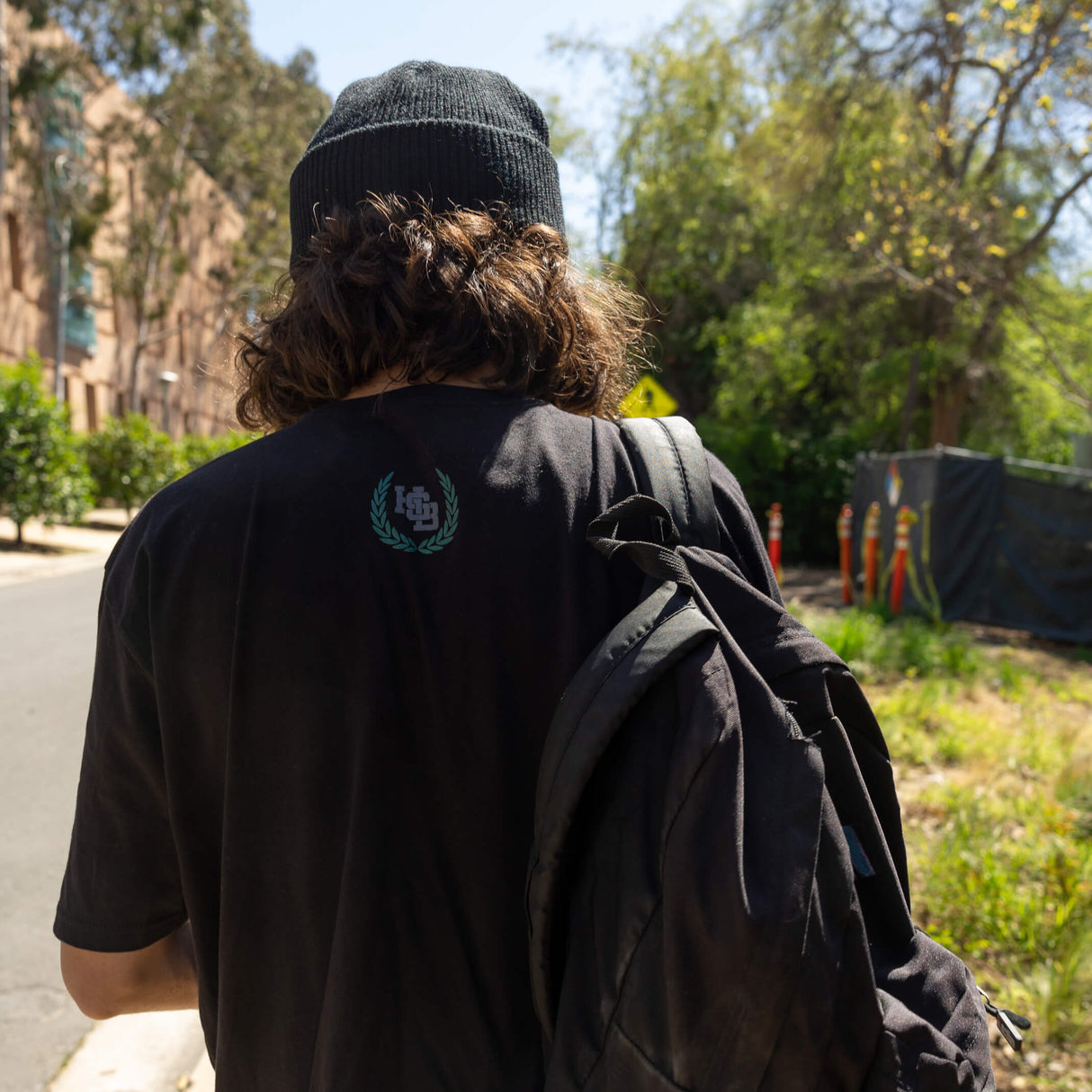 Black varsity tee back view with small green crest logo