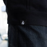 Black hoodie fabric close-up with white flame logo patch near side seam