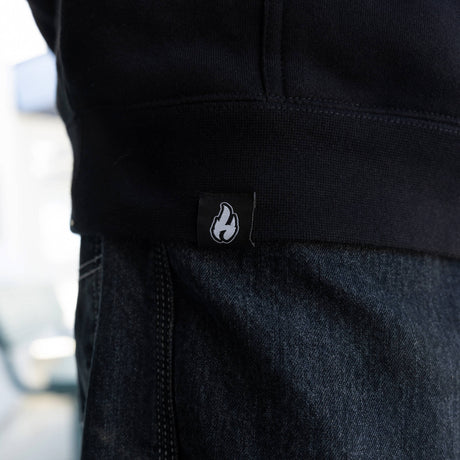 Black hoodie hem with small flame logo patch