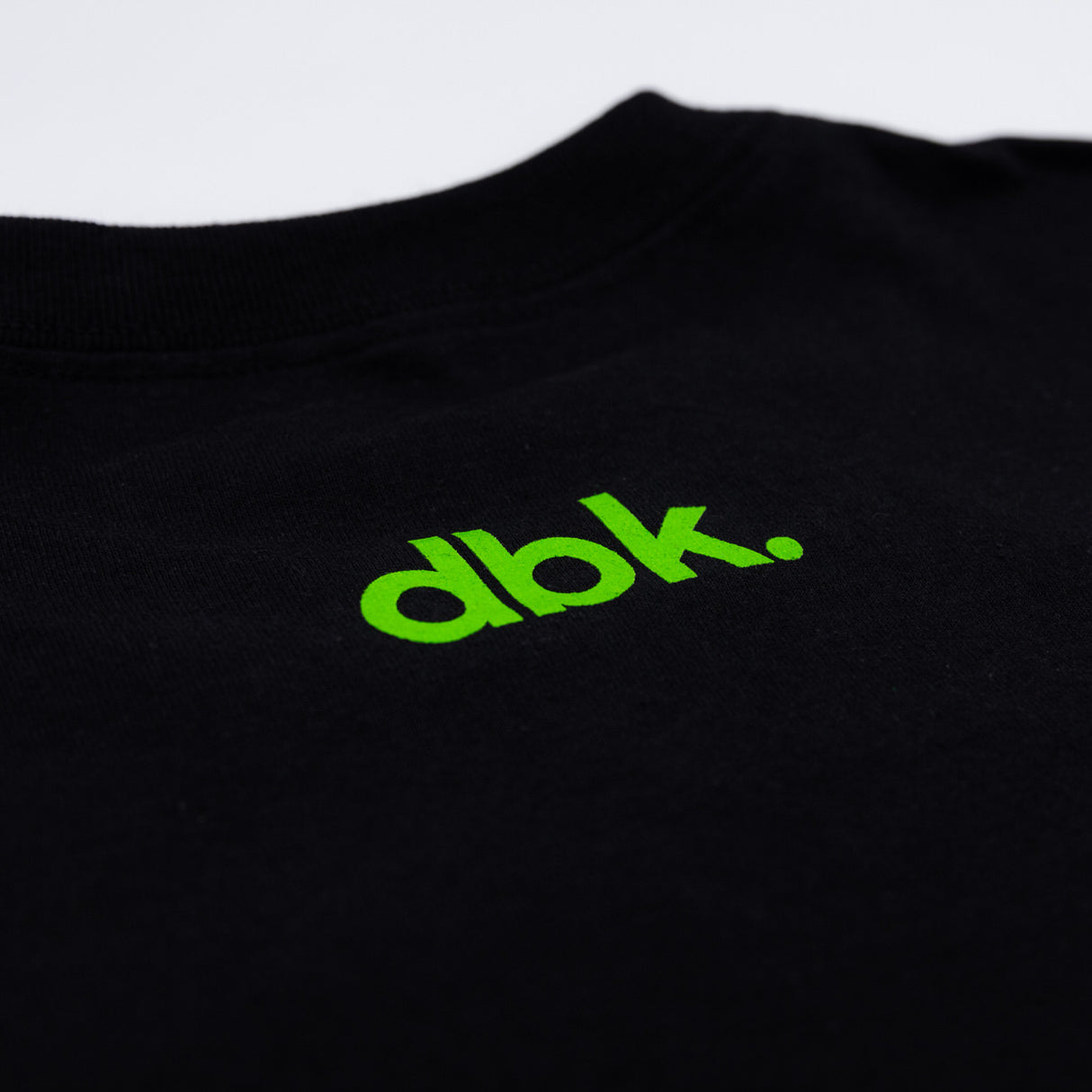 Youth black T-shirt fabric close-up with green dbk. logo