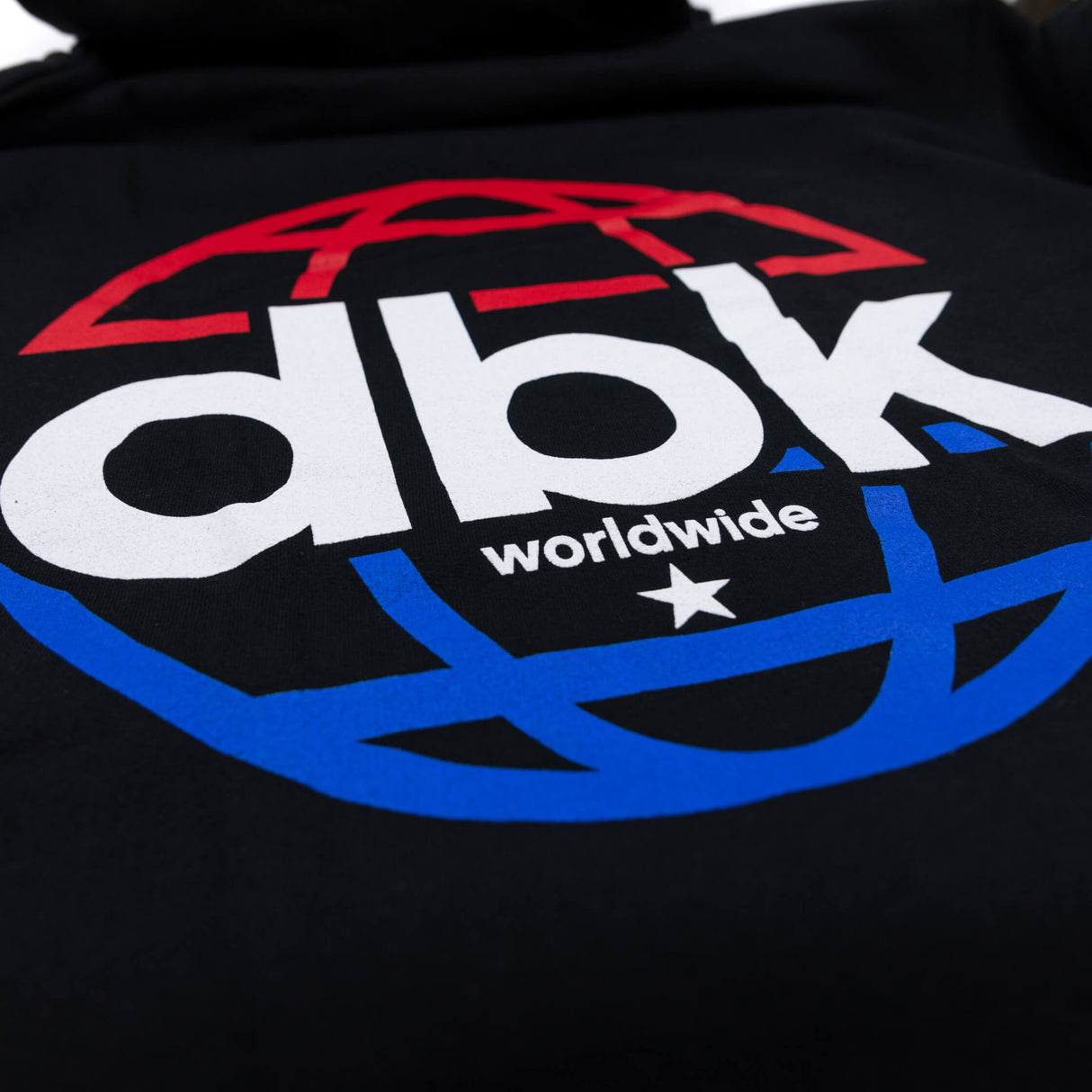 Black hoodie close-up of “dbk worldwide” logo graphic with red, white and blue colors