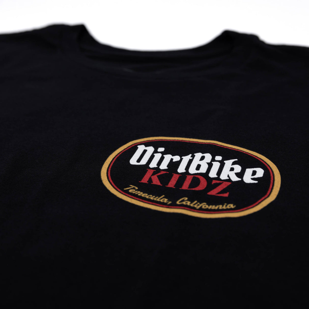 Premium tall tee logo close-up, black fabric with DirtBike KIDZ oval chest logo