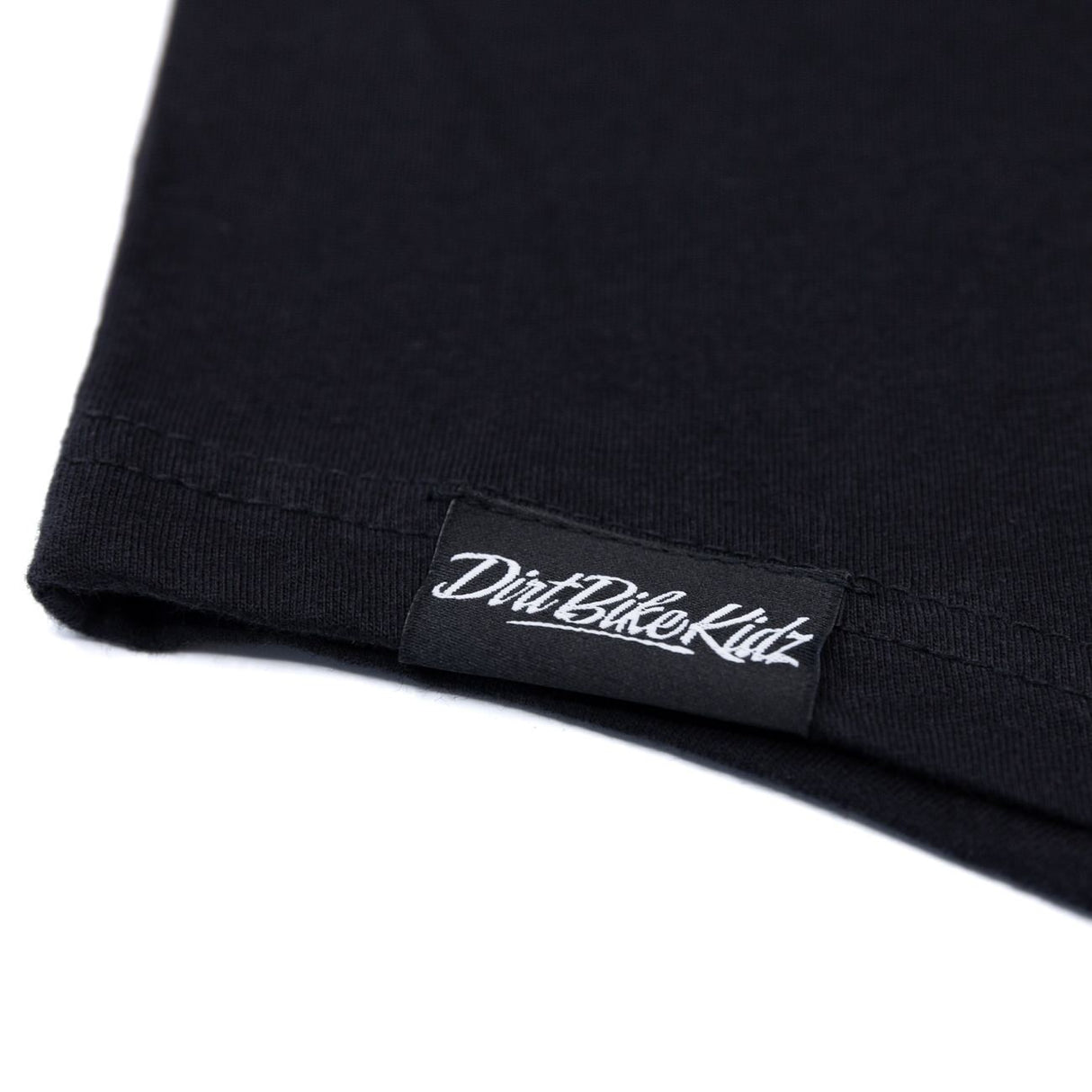 Black T-shirt hem with stitched fabric tag patch at the bottom.