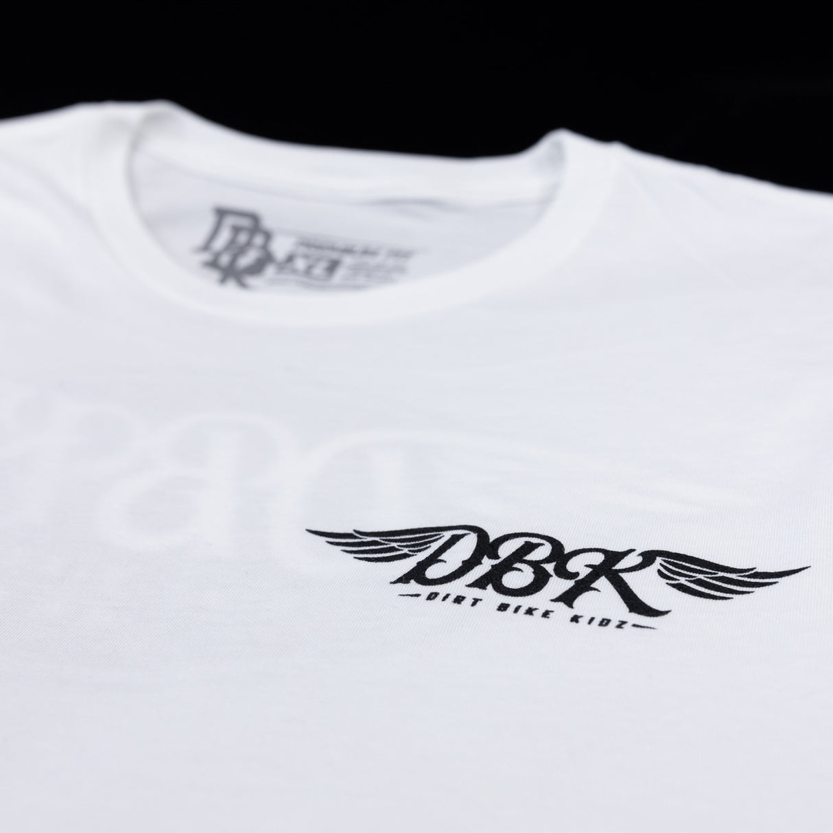 White tall tee with crew neck and small winged DBK logo printed on chest
