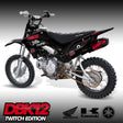 Black pit bike with red graphics, knobby tires, and front fork suspension—side view