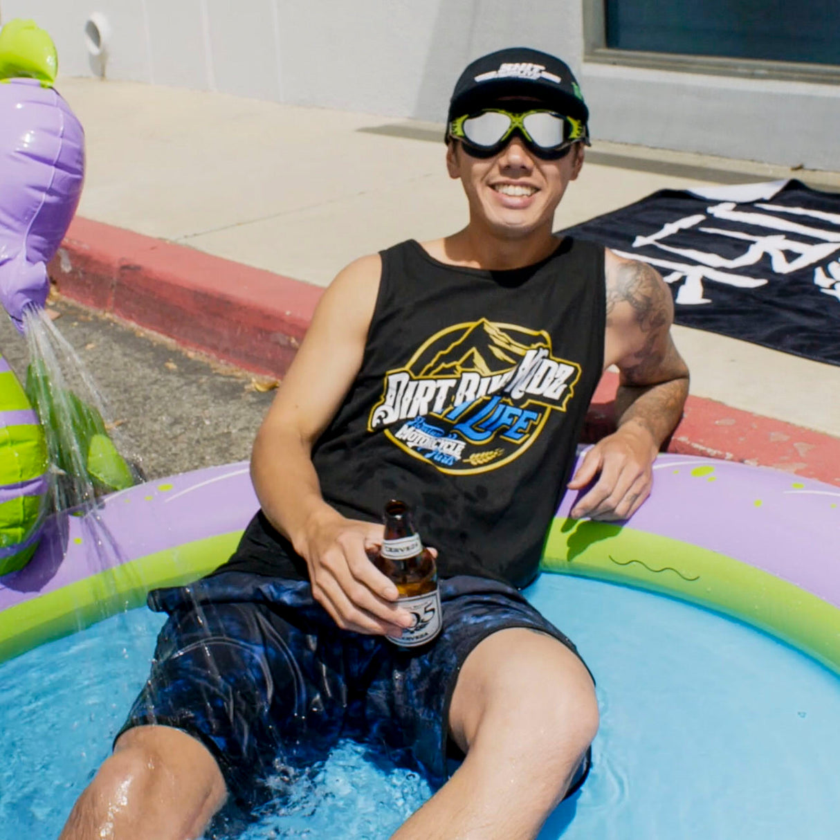 Black tank top with 'Dirt Bike Kidz' 'High Life' graphic, worn by person in pool